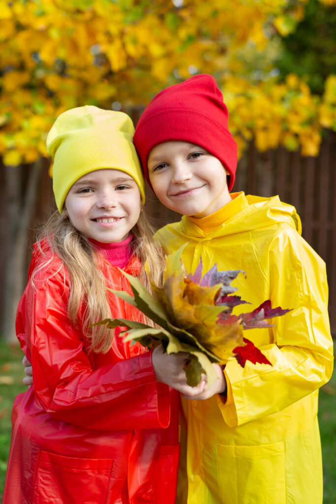 Portrait of a boy and a girl with a bouquet of yellow leaves on an autumn day